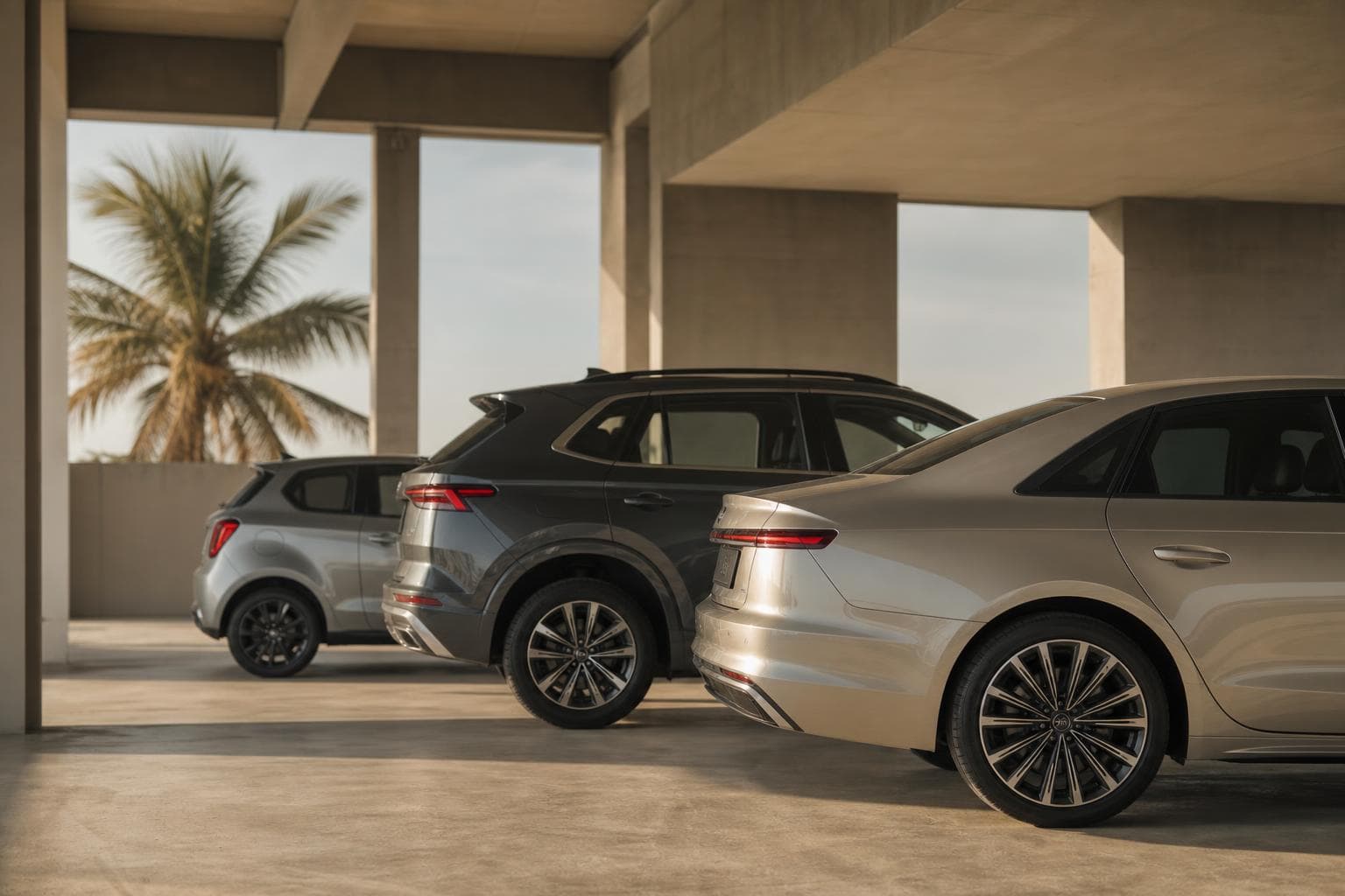 A compact car, an SUV and a sedan parked in a bright garage